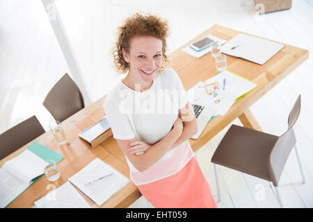 Porträt der Frau mit verschränkten Armen und lächelnd in Büro Stockfoto