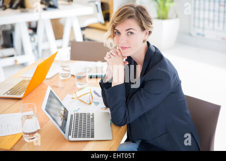 Porträt Frau mit Laptop im Büro am Schreibtisch sitzen Stockfoto