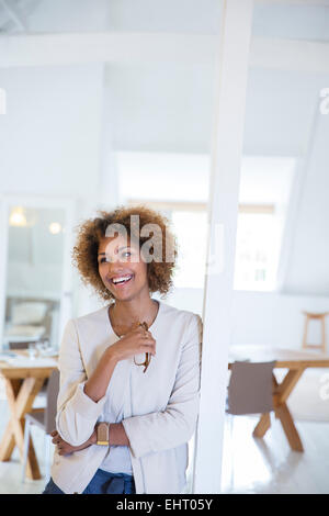 Porträt der Frau stützte sich auf Spalte im Büro lächelnd Stockfoto