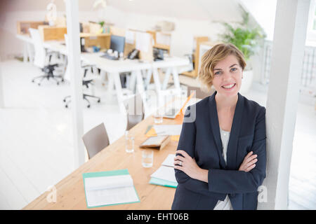 Porträt der Frau stützte sich auf Spalte im Büro lächelnd Stockfoto