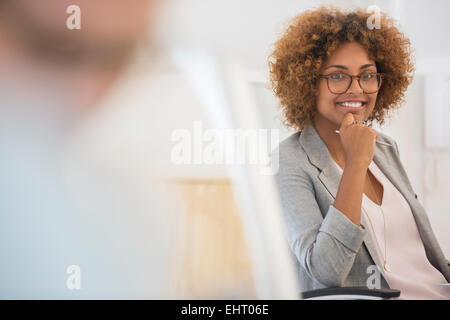 Porträt der Frau sitzen im Büro, trägt Brille und lächelt Stockfoto