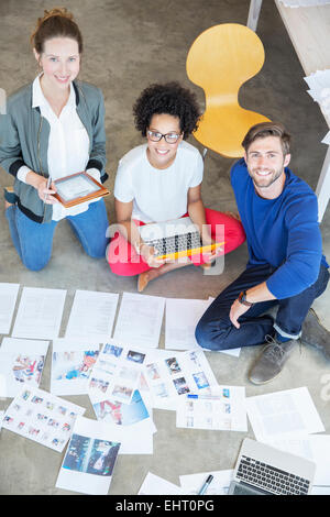 Porträt von drei jungen Leuten am Boden sitzen und arbeiten zusammen Stockfoto