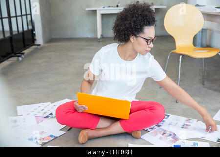 Junge Frau am Boden sitzen und arbeiten mit laptop Stockfoto