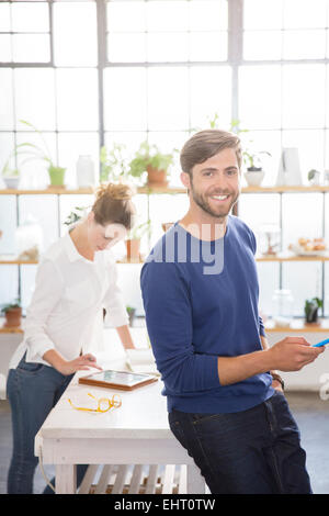 Zwei junge Menschen, die mit verschiedenen tragbaren Geräten in der heimischen Küche Stockfoto