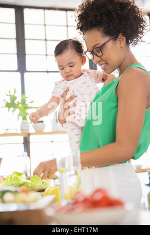 Frau mit Baby Girl Zubereitung in der Küche Stockfoto