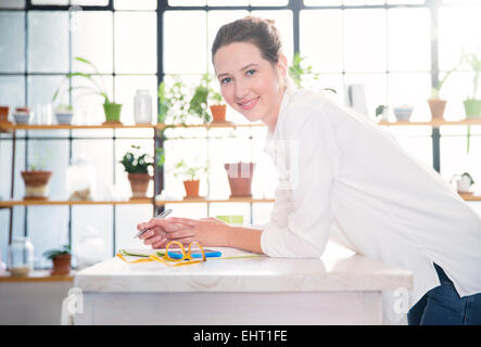 Porträt der jungen Frau am Küchentisch gelehnt Stockfoto