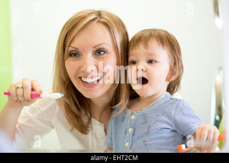Mutter lehrt Kind Zähne putzen Stockfoto