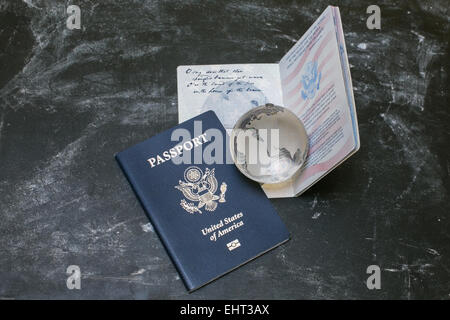 Zwei US-Reisepässe auf schwarzem Hintergrund. Amerikanische Staatsbürgerschaft. Reisen auf der ganzen Welt. Kleine Glaskugel auf geöffneten Dokument. Stockfoto