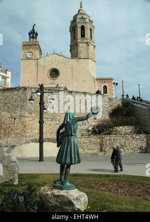 Statue des Mädchens hält jede Menge Trauben und San Bartolomé y Santa Tecla Kirche im Badeort Sitges, Katalonien, Spanien Stockfoto