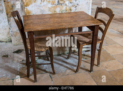 Alten Holztisch und zwei Holzstühle auf dem Boden der alten Fliesen. Stockfoto