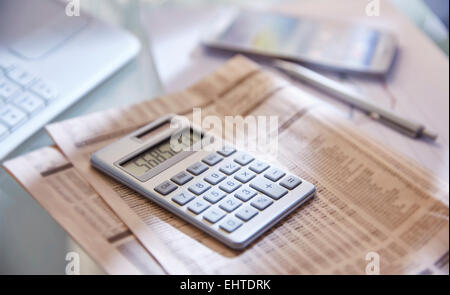 Taschenrechner, Nahaufnahme, Zeitung und Stift auf Schreibtisch Stockfoto