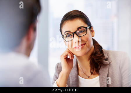 Lächelnde Frau in Gläsern im Büro mit client Stockfoto