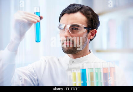 Mann im Labor Fläschchen mit blauer Flüssigkeit zu betrachten Stockfoto