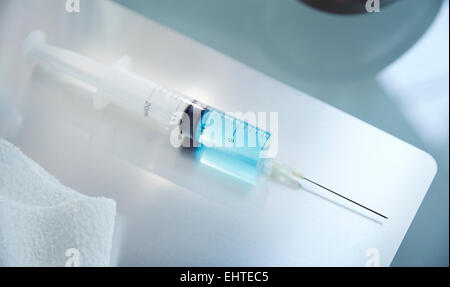 Ansicht der Spritze mit blauer Flüssigkeit auf Tisch im Labor Stockfoto