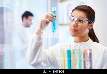 Frau im Labor Fläschchen mit blauer Flüssigkeit zu betrachten Stockfoto
