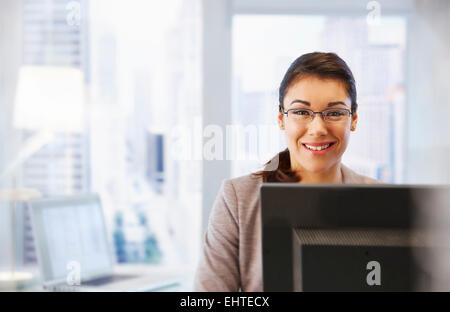 Weibliche Büroangestellte sitzen am Schreibtisch mit Computer, Porträt Stockfoto