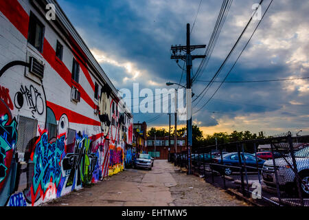 Graffiti und geparkte Autos in einer Gasse bei Sonnenuntergang in Baltimore, Maryland. Stockfoto