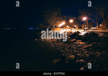 Lampen und Felsen entlang der Küste der Chesapeake Bay in der Nacht in Havre de Grace, Maryland. Stockfoto