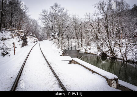 Schneebedeckten Eisenbahnschienen und einem Bach in ländlichen Carroll County, Pennsylvania. Stockfoto