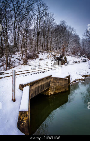 Schneebedeckte Eisenbahnbrücke über einen Bach im ländlichen Carroll County, Maryland. Stockfoto