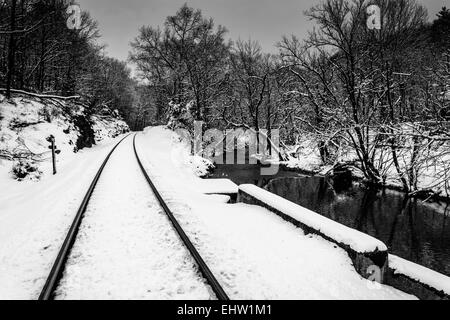 Verschneite Bahngleis und Creek im ländlichen Carroll County, Maryland. Stockfoto