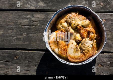 Gegrilltes mariniertes Hähnchen in Aluminium-Folie-Fach. Über alte hölzerne Picknick-Tisch in Stücke geschnitten Stockfoto