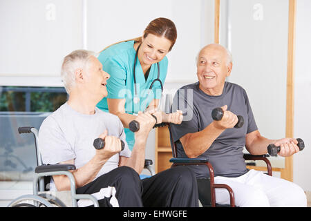 Zwei alte Männer im Rollstuhl heben Hanteln in der Physiotherapie Stockfoto