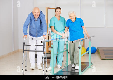 Zwei ältere Leute zu Fuß ausüben in der Physiotherapie mit Physiotherapeuten Stockfoto