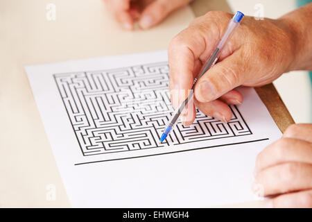 Hand der ältere Mann mit Stift tun der Gedächtnistraining mit einem Papier-Labyrinth Stockfoto