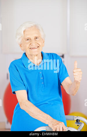 Glückliche senior Frau hält ihre Daumen in einem Pflegeheim Stockfoto