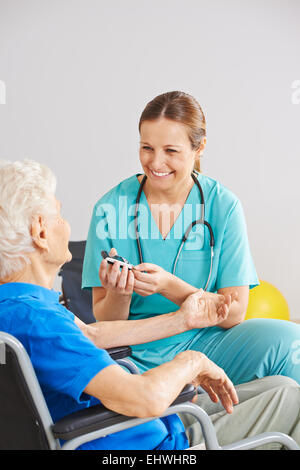Geriatrische Betreuer tun Blutzucker Moni für alte Diabetes-Patienten Stockfoto