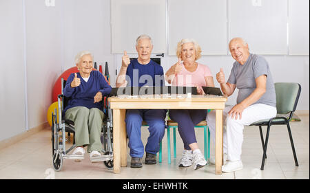 Gruppe von Senioren Daumen hochhalten und ein Spiel in Pflegeheim Stockfoto