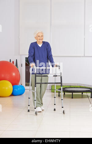 Glückliche senior Frau mit Walker Ausübung zu Fuß in der Physiotherapie Stockfoto