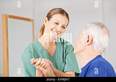 Lächelnd geriatrische Krankenschwester Hand in Hand mit senior Greis Stockfoto