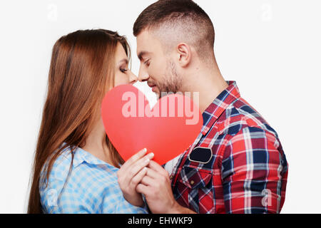 Junges Paar ist hinter roten Herzen küssen. Stockfoto