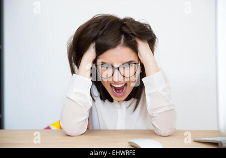 Am Tisch sitzen und schrie wütend Geschäftsfrau Stockfoto