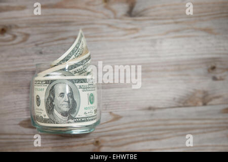 Draufsicht Banknoten in Geld Glas auf alten Schreibtisch aus Holz mit textfreiraum auf Seite. Stockfoto