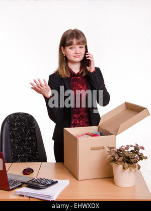 Frau von ihrem Job im Büro gefeuert sammelt persönliche Gegenstände in einer Box und am Telefon sprechen Stockfoto