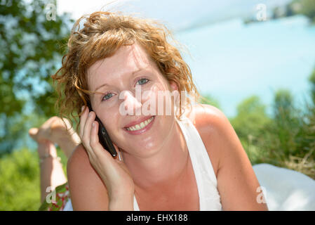 rothaarige Frau im Rasen Telefon liegen Stockfoto