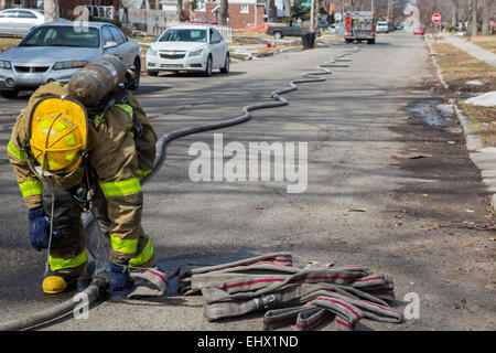 Detroit, Michigan - eine Feuerwehr verbindet Schläuche während des Kampfes ein Feuer zerstörte ein frei Haus in Detroit. Stockfoto