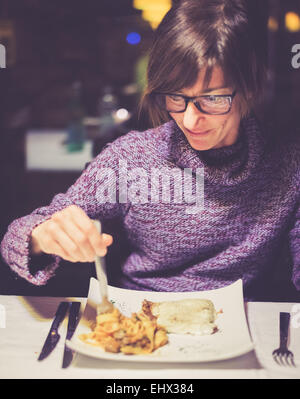 Fröhliche junge Dame mit Abendessen im italienischen Restaurant. Kreuz verarbeitet mit Instagram Stil, Tiefenschärfe, dunklen Hintergrund. Stockfoto