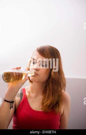 Junge rothaarige Frau trinkt Bier aus der Flasche, München, Bayern, Deutschland Stockfoto