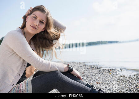 Porträt hübsche junge Frau sitzt am Ufer Stockfoto