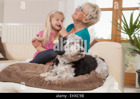 Ältere Frau mit Hund und Enkelin Lachen im Wohnzimmer, Bayern, Deutschland Stockfoto