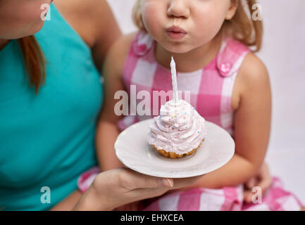 glückliche Mutter und Mädchen Kuchen Kerze ausblasen Stockfoto