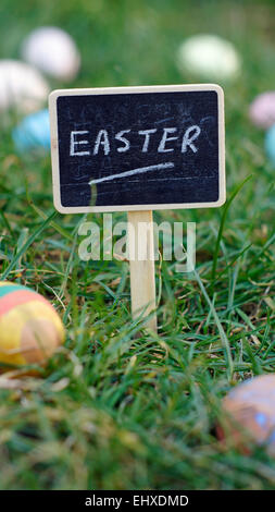 Ostern, geschrieben auf einer Tafel stehen im Rasen zwischen Ostereiern Stockfoto