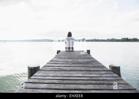 Frau allein Steg See ruhig sitzen Stockfoto