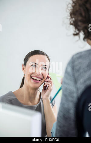 Geschäftsfrau, die in einem Büro mit Handy spricht, München, Bayern, Deutschland Stockfoto