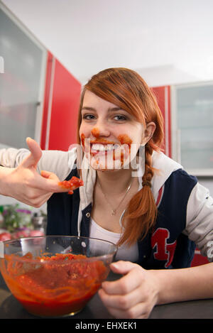 Glückliche junge Frau Essen Tomatensoße in Küche, München, Bayern, Deutschland Stockfoto