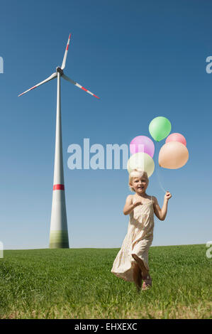 Mädchen läuft mit Haufen Luftballons in Windparks, Bayern, Deutschland Stockfoto